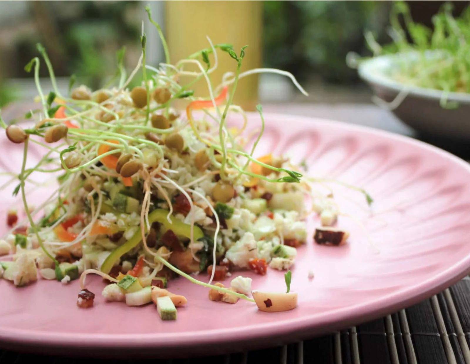 Plato con germinados frescos sobre una ensalada de coliflor y frutos secos